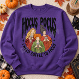 Hocus Pocus DTF transfer featuring three illustrated witch characters sipping iced coffee, framed in a circle with stars and 'I Need Coffee To Focus' lettering Shown on a Purple crewneck sweatshirt.