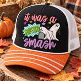 It Was a Graveyard Smash Halloween DTF transfer with two cartoon ghosts, a crypt, colorful stars, and bold patterned lettering Shown on a black foam front, orange striped bill, white mesh back trucker hat.