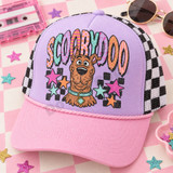 Scooby-Doo retro pop-art DTF transfer with distressed face, collar and tag, colorful patterned bubble letters spelling SCOOBYDOO, and scattered stars over a black checker pattern Shown on a lavender front panel with pink pre-curved bill and black-and-white checkered mesh back trucker hat.