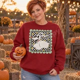 Friendly ghost dog with bat-like ears and red collar DTF transfer on a checkered background with gold stars in a scalloped frame Shown on a Cardinal Red crewneck sweatshirt.