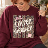 Coffee Weather DTF transfer with cream brush-script lettering over a distressed leopard print background, pink bow, and pink steaming coffee mug Shown on a Maroon crewneck sweatshirt.