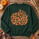 Howdy pumpkin DTF transfer with hand-lettered script, curling vine tendril, and leopard-print spots on a dark sweatshirt Shown on a Forest crewneck sweatshirt.