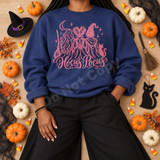 Hocus Pocus DTF transfer with pink line-art illustration of three witches from behind under a crescent moon, with broom, black cat, and script lettering Shown on a Indigo Blue crewneck sweatshirt.