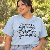 The Enemy Thought He Had Me But Jesus Said You Are Mine faith DTF transfer in black brush-script lettering with hand-drawn sparkle stars Shown on a Ice Blue t-shirt.