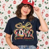 Love Came Down nativity DTF transfer with patchwork-style LOVE lettering, baby Jesus in a manger, a red green and gold ribbon bow, starburst, and Luke 2:11 scripture citation Shown on a True Navy t-shirt.