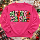 Merry & Bright bubble-letter Christmas DTF transfer in pink, green, and red with glowing string lights Shown on a Heliconia crewneck sweatshirt.