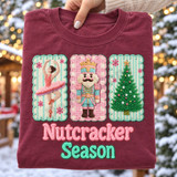 Nutcracker Season DTF transfer with yarn-embroidered-look ballerina, crowned nutcracker soldier, and Christmas tree patches on candy-striped backgrounds and chenille lettering Shown on a Wine t-shirt.