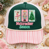 Nutcracker Season DTF transfer with yarn-embroidered-look ballerina, crowned nutcracker soldier, and Christmas tree patches on candy-striped backgrounds and chenille lettering Shown on a forest green front panel, blush pink striped bill, cream rope, white mesh back trucker hat.