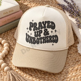 Prayed Up & Unbothered DTF transfer in black bubble-letter lettering with halftone texture and sparkle star accents Shown on a Ivory front / Khaki bill / Natural mesh trucker hat.
