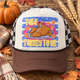 Talk Turkey To Me Thanksgiving DTF transfer with cartoon roasted turkey chatting on a retro telephone, surrounded by orange stars on a blue starred background Shown on a ivory front panel, brown bill, black-and-white checkered mesh back trucker hat.
