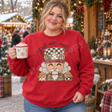 Y'all Are Nuts folk-art nutcracker DTF transfer with checkered crown, plaid and camo uniform, and fluffy white beard on a red sweatshirt Shown on a Red crewneck sweatshirt.
