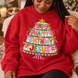 Happy Birthday Jesus DTF transfer featuring a folk-art Christmas tree-shaped cake with garlands, bows, a gold star topper, and rainbow lettering Shown on a Cardinal Red crewneck sweatshirt.