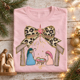 Nativity scene DTF transfer with Mary, Joseph, and baby Jesus beneath a leopard-print bow and glittering pink star Shown on a Blossom t-shirt.