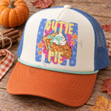 Cutie Pie DTF transfer featuring a hand-drawn pumpkin pie slice with whipped cream and mint bow, pink scalloped doily, orange stars, and blue star-striped background Shown on a cream front panel, burnt-orange bill, denim-blue mesh back, mint rope trucker hat.