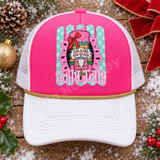 Holly Jolly nutcracker DTF transfer with pink and green nutcracker face, red bow, gold crown, in a pink scalloped frame over a mint polka-dot striped background with bold bubble lettering Shown on a Hot pink front panel, white pre-curved bill, white mesh back with gold rope trucker hat.