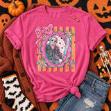 Cutesy Horror DTF Transfers | Pastel Spooky Icons Collection, pastel Halloween design featuring a masked horror character framed by a pink bow, stars, and colorful accents on a bright pink T-shirt.