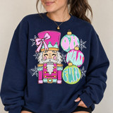 Pink and mint nutcracker DTF transfer with sugarplum bow and Oh What Fun ornament lettering surrounded by snowflakes Shown on a Navy crewneck sweatshirt.