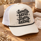 Sweetly Saved. Slightly Savage. retro bubble letter DTF transfer in black halftone texture with sparkly star accents on a pink shirt Shown on a cream foam front panel with black rope and white mesh back trucker hat.