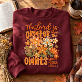 The Lord is Greater Than the Giants You Face DTF Transfer | Faith Floral Design, orange and cream floral scripture design displayed on a burgundy sweatshirt beside an open Bible and autumn leaves.