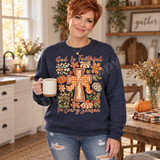 God Is Faithful In Every Season DTF transfer with orange wooden cross, plaid bow, and polka-dot, gingham, and leopard-print fall daisies and pumpkins Shown on a Heather Dark Navy crewneck sweatshirt.