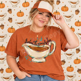 All About the Gravy Baby DTF Transfer | Hand-Painted Thanksgiving Design, woman modeling a rust-colored shirt featuring a hand-painted gravy boat and playful Thanksgiving lettering, with a pumpkin and gravy boat backdrop.