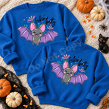 Frikin' Batty Cute Bat DTF Transfer | Halloween Design, playful gray bat with pink ears and purple wings printed on blue sweatshirts, styled with pumpkins and Halloween decorations.