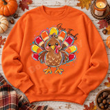 Give Thanks Turkey DTF Transfer | Cute Thanksgiving Fall Design, colorful cartoon turkey with rainbow feathers and “Give Thanks” lettering displayed on an orange sweatshirt among pumpkins, autumn leaves, and a pumpkin spice candle.
