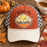 Here For The Mashed Potatoes DTF Transfer | Funny Thanksgiving Food Design, colorful mashed potatoes bowl with playful lettering displayed on a rust-orange and cream trucker hat surrounded by autumn pumpkins and fall leaves.