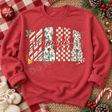Christmas Mama DTF transfer with chunky block letters filled in candy-cane stripe, holly, checkerboard, and leopard patterns, topped with red cursive mama script and holiday bow, bell, and candy cane accents Shown on a Heather Scarlet Red crewneck sweatshirt.