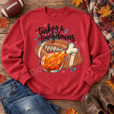 Turkey & Touchdowns DTF Transfer | Thanksgiving Football Design, colorful turkey drumstick and football graphic with “Turkey & Touchdowns” lettering, displayed on a red sweatshirt among autumn leaves and football-themed props.