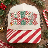 Grandma Christmas DTF transfer with block letters in candy cane, checkerboard, snowflake, and leopard patterns, topped with red cursive script and holly, bow, bell, and candy cane accents Shown on a cream front panel with red and white candy-cane striped pre-curved bill and leopard print mesh back trucker hat.