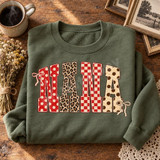 Nana Patchwork DTF Transfer | Polka Dot, Leopard & Checkerboard Word Art, colorful “NANA” lettering with polka dot, leopard print, and red checkerboard patterns displayed on a folded olive green sweatshirt.