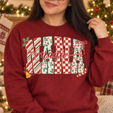 NANA Christmas DTF transfer with candy cane stripe, holly, checkerboard, and leopard print letters, holly leaves, a red bow, gold jingle bell, candy cane, and red script 'nana' overlay Shown on a Antique Cherry Red crewneck sweatshirt.