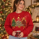 Whimsical Christmas trees DTF transfer featuring green buffalo plaid, red buffalo plaid, and leopard print trees with gold stars, bows, and scattered snowflakes Shown on a Cardinal Red crewneck sweatshirt.