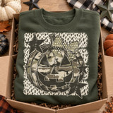 Distressed camouflage jack-o-lantern DTF transfer with polka-dot bow and charcoal stars on a textured dot-print background Shown on a Military Green crewneck sweatshirt.