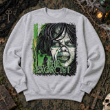 The Exorcist DTF transfer with grungy green and black distressed illustration of a demonic possessed face and a shadowy figure in a hat before a lit doorway Shown on a Ash crewneck sweatshirt.