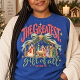 The Greatest Gift of All nativity scene DTF transfer with Mary, Joseph, baby Jesus, shepherd and wise men under a pine garland stable, Matthew 1:21 verse Shown on a Heather Deep Royal crewneck sweatshirt.