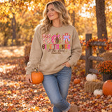 Give Thanks to the Lord DTF transfer with a patchwork checkered bow, plaid and polka dot pumpkin, colorful patterned cross, and Psalm 136:6 lettering Shown on a Sand crewneck sweatshirt.