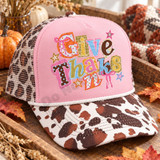 Give Thanks scrapbook-style word art DTF transfer with mixed patterned paper letters, pink ribbon bows, and sparkly stars Shown on a pink front panel, white rope, leopard mesh back trucker hat.