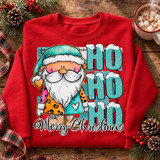 Watercolor Santa gnome DTF transfer with leopard and teal patchwork coat, snow-capped HO HO HO lettering, and Merry Christmas script on plaid background Shown on a Cherry Red crewneck sweatshirt.