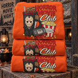 Horror Movie Club DTF transfer with hockey-masked slasher villain holding a bloody machete, Camp Crystal Lake sign, candy bucket, popcorn, and Horror Nightmares VHS tape design Shown on a Orange crewneck sweatshirt.