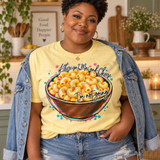 Hand-painted bowl of macaroni and cheese DTF transfer with glittery pink, teal, and gold rim, confetti dots, and 'If there isn't Mac and Cheese, I'm not going' script lettering Shown on a Butter t-shirt.