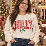 Jolly-ish Christmas DTF transfer with JOLLY in red buffalo plaid, leopard, polka dot, distressed, and checkerboard patterns above hand-lettered green cursive 'ish.' Shown on a Ivory t-shirt.