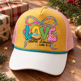 LOVE came down Christmas DTF transfer with patterned bubble letters, swaddled baby in a manger, multicolor ribbon bow, and Luke 2:11 scripture Shown on a mustard gold front panel, white bill, blush pink mesh back, teal rope trucker hat.