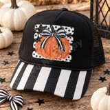Hand-illustrated orange pumpkin DTF transfer with black-and-white striped bow, black stars, and polka-dot background Shown on a Black front panel / black-and-white striped bill / black mesh back trucker hat.