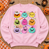 Kawaii Halloween pumpkin grid DTF transfer with nine patterned jack-o-lanterns, bats, spiderwebs, and sparkles on a teal shirt Shown on a Light Pink crewneck sweatshirt.