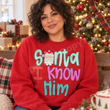 Santa I Know Him Christmas DTF transfer with hand-drawn Santa face replacing the letter A in bold mixed-color bubble lettering Shown on a Cherry Red crewneck sweatshirt.