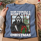 Have Yourself a Scary Little Christmas DTF transfer with Ghostface-style killer holding a knife and wrapped present at a snowy window with Christmas tree Shown on a Chambray t-shirt.