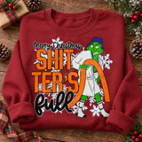 Merry Christmas Shitter's Full DTF transfer with grumpy green Christmas character dragging an orange hose in front of snowflakes Shown on a Antique Cherry Red crewneck sweatshirt.