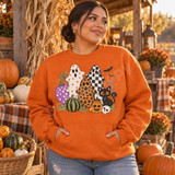 Hand-drawn Halloween DTF transfer with star, leopard print, and checkerboard patterned ghosts, polka-dot and striped pumpkins, a jack-o'-lantern, a black cat with a purple star collar, a skull, bats, and a spiderweb in crayon-textured illustration style Shown on a Orange crewneck sweatshirt.